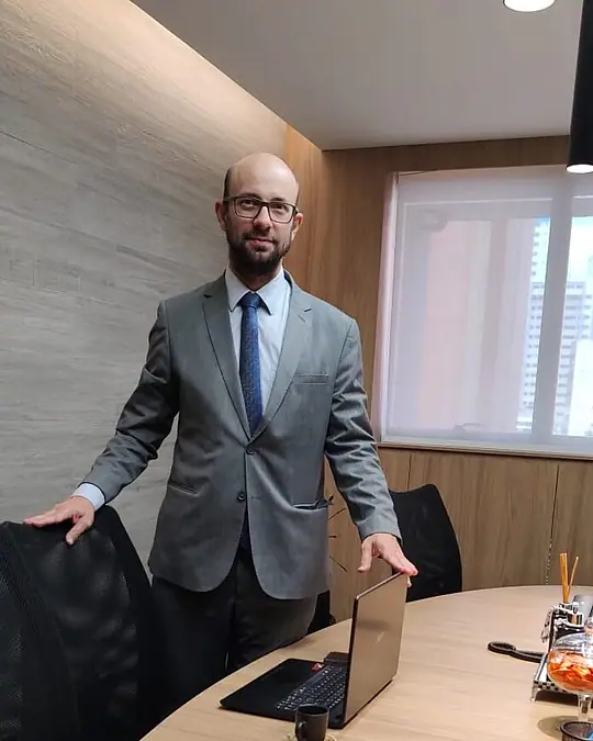 Bruno de Bruno, advogado, de terno, em pé na sala de reuniões do escritório